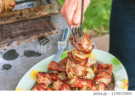 Cooked kebabs on the grill with smoke. Fresh brown BBQ meat cooked on an outdoor grill Cooked kebabs on the grill with smoke. Fresh brown BBQ meat cooked on an outdoor grill 114033864
