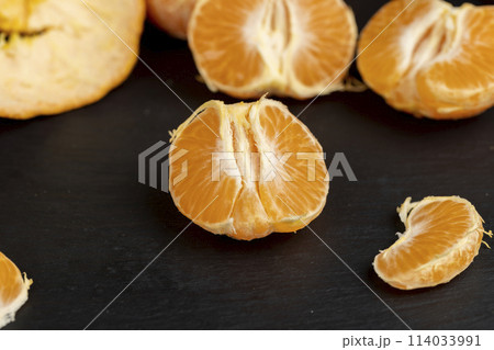 a large number of orange citrus fruits on a black slate surface a large number of orange citrus fruits on a black slate surface 114033991