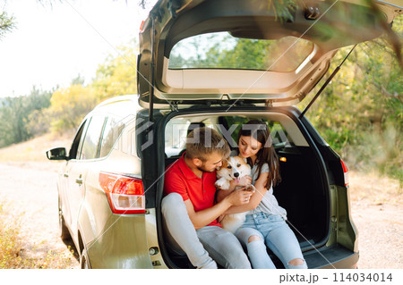 Happy couple is petting their beloved corgi dog. Concept of lifestyle, vacation, travel, family. Happy couple is petting their beloved corgi dog. Concept of lifestyle, vacation, travel, family. 114034014