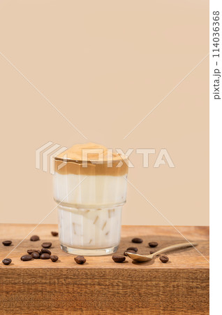 Dalgona coffee. Whipped instant coffee in a glass on a wooden table with coffee beans 114036368
