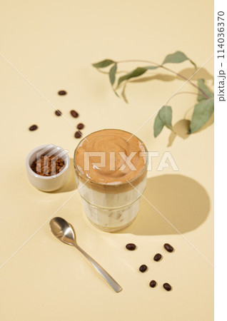 Vegan dalgona coffee. Whipped instant iced coffee with soy milk in a glass on yellow background Vegan dalgona coffee. Whipped instant iced coffee with soy milk in a glass on yellow background 114036370