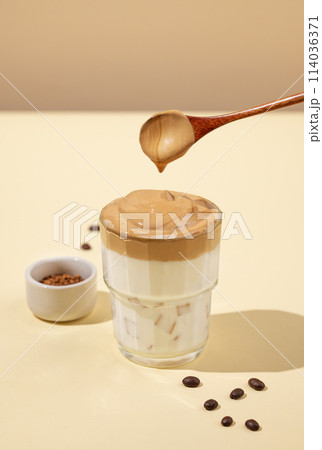 Dalgona coffee. Whipped instant coffee with ice and milk on a yellow background with shadow. 114036371