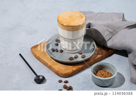 Dalgona coffee. Whipped instant coffee in a glass on a wooden board with coffee beans Dalgona coffee. Whipped instant coffee in a glass on a wooden board with coffee beans 114036388