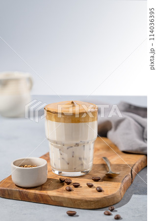 Dalgona coffee. Whipped instant coffee in a glass on a wooden board with coffee beans Dalgona coffee. Whipped instant coffee in a glass on a wooden board with coffee beans 114036395