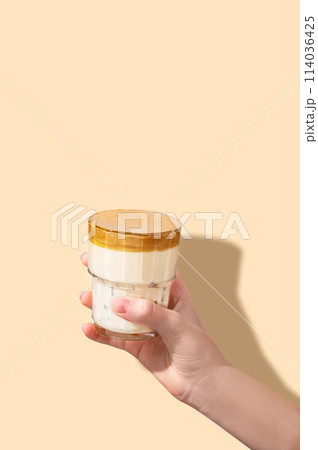 Dalgona coffee. A hand holds a glass of whipped and instant iced coffee and milk in a glass  114036425