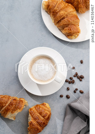 A cup of aromatic cappuccino coffee and fresh croissants on a blue background. 114036467
