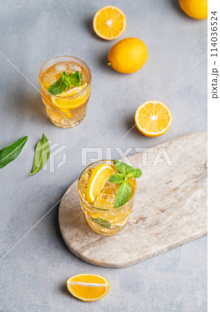 Iced tea with lemon, mint in a glass on a marble board on a light background with citrus fruits. 114036524