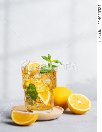 Iced drink with lemon, mint in a glass on a on a light background with shadow and citrus fruits. 114036525