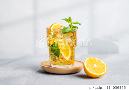 Iced tea with lemon, mint in a glass on light background with shadow and citrus fruits. 114036526