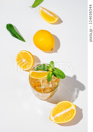 Flat lay of Iced tea with lemon and mint on white background with a shadow and citrus fruits. 114036544