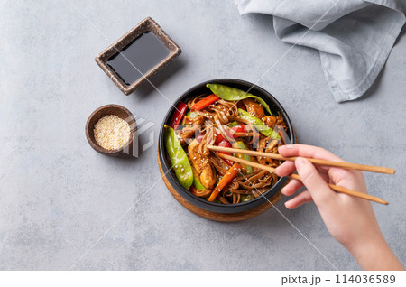 Stir-fry with soba noodles, meat and vegetables in black plate on a light background  114036589