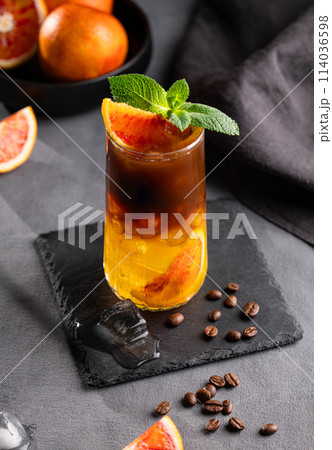 Coffee with orange juice (bumble) in a tall glass with ice and mint on a dark background Coffee with orange juice (bumble) in a tall glass with ice and mint on a dark background 114036598