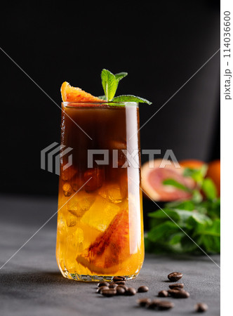Coffee with orange juice (bumble) in a tall glass with ice and mint on a dark background 114036600