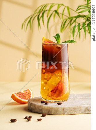 Americano coffee with orange juice (bumble) in a tall glass with ice and mint on a yellow background 114036605