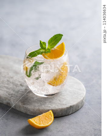 Lemonade tonic drink with fresh lemon, mint and ice on a marble board on a light background. Lemonade tonic drink with fresh lemon, mint and ice on a marble board on a light background. 114036634