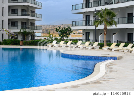 Closeup of towels on lounge chairs near a luxury swimming pool 3 114036918