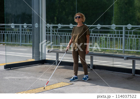 An elderly blind woman is waiting for transport at a bus stop. An elderly blind woman is waiting for transport at a bus stop. 114037522