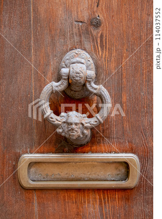 Antique details on an old wooden door. Medieval door handle. 114037552