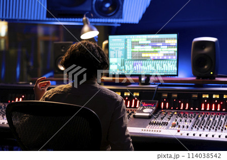 Audio expert working on editing music with daw software interface, processing and mixing sounds in control room. Skilled engineer operating on control panel board console, mixer station. Audio expert working on editing music with daw software interface, processing and mixing sounds in control room. Skilled engineer operating on control panel board console, mixer station. 114038542