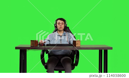 Woman being excited about winning online gaming championship, playing video games on computer sitting at desk. Gamer having fun celebrating her success and victory, greenscreen backdrop. Camera B. 114038600