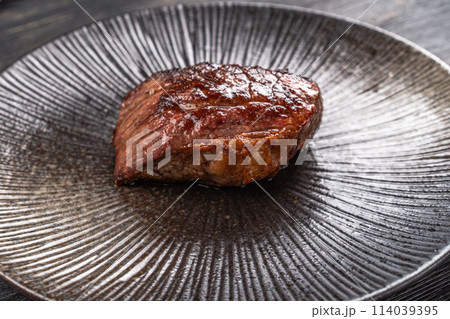 Fresh juicy delicious beef steak on a dark background. Meat dish with spices and herbs 114039395