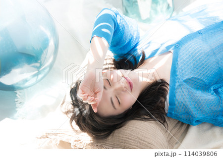 眩しい夏の日差しで寝転がる目を閉じる美しい女性　海や夏の日焼けやUVの美容イメージなどにも　俯瞰 114039806