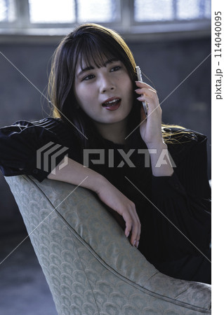シックな部屋のソファでスマホで電話する若い女性 シックな部屋のソファでスマホで電話する若い女性 114040095