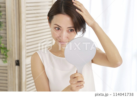 髪の毛を鏡で確認する中年女性 髪の毛を鏡で確認する中年女性 114041738
