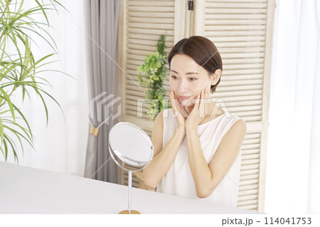自宅でフェイシャルケアをする中年女性 自宅でフェイシャルケアをする中年女性 114041753