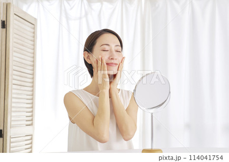 自宅でフェイシャルケアをする中年女性 自宅でフェイシャルケアをする中年女性 114041754