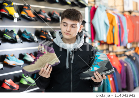 Guy examine view item of autumn comfortable trecking shoes Guy examine view item of autumn comfortable trecking shoes 114042942
