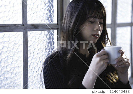 窓際でコーヒーを飲む若い女性 114043488