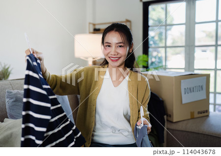 Asian woman select clothes at home to put in a donation box second hand clothes 114043678