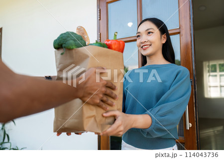 Asian young delivery man delivering package to female customer at home Asian young delivery man delivering package to female customer at home 114043736
