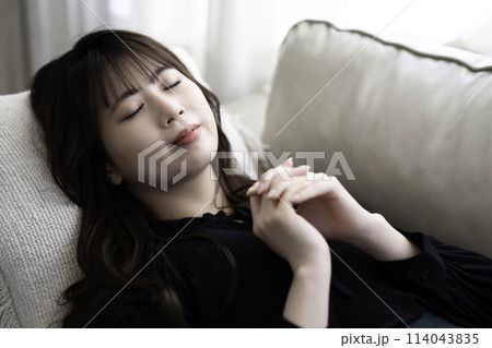 ソファに寝転んでくつろぐ若い女性 114043835