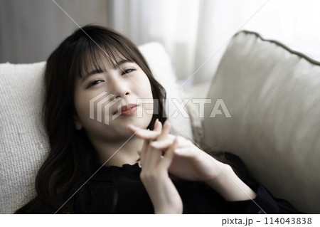 ソファに寝転んでくつろぐ若い女性 ソファに寝転んでくつろぐ若い女性 114043838