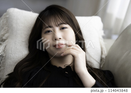 ソファに寝転んでくつろぐ若い女性 114043848