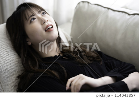 ソファに寝転んでくつろぐ若い女性 114043857
