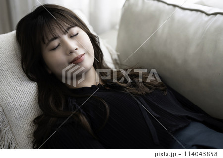 ソファに寝転んでくつろぐ若い女性 114043858