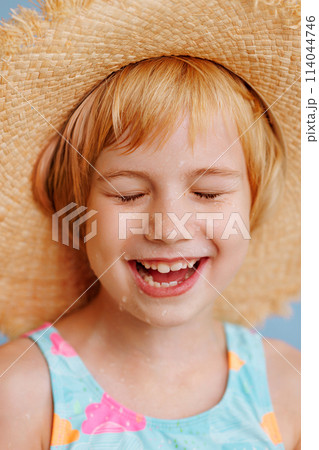 A young girl is smiling and wearing a straw hat A young girl is smiling and wearing a straw hat 114044746