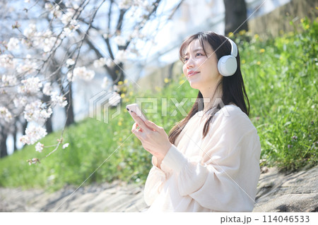 桜の下で音楽を聴く女性 114046533