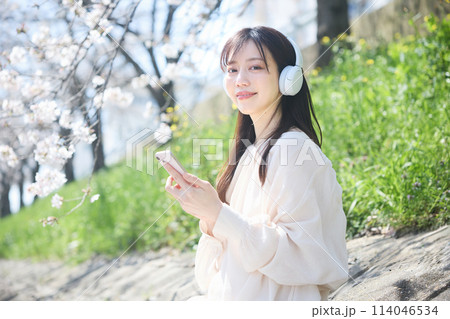 桜の下で音楽を聴く女性 114046534