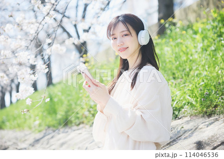 桜の下で音楽を聴く女性 114046536