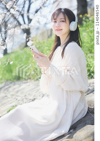 桜の下で音楽を聴く女性 114046540