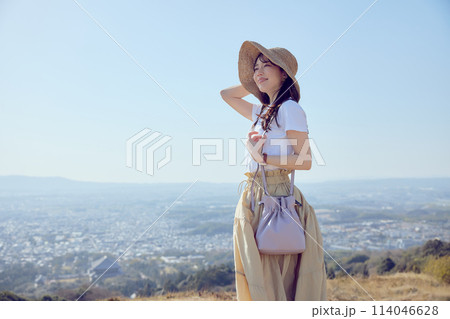 丘の上で遠くを見つめる女性 114046628