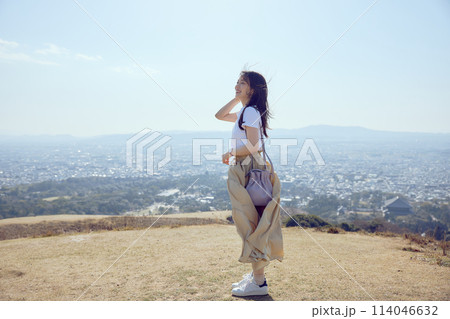 丘の上で遠くを見つめる女性 114046632