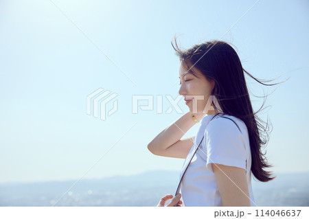 丘の上で遠くを見つめる女性 114046637