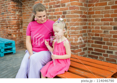 Blonde little girl with cochlear implant playing with her mother outdoor. Hear impairment deaf and health concept. Disability and inclusion. Copy space 114046790