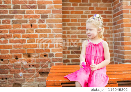 Child girl with hearing aids and cochlear implants having fun outdoor speak and playing. Copy space and empty place for advertising. Inclusion and disability. 114046802