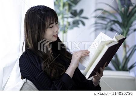 休日にソファで読書する若い女性 114050750